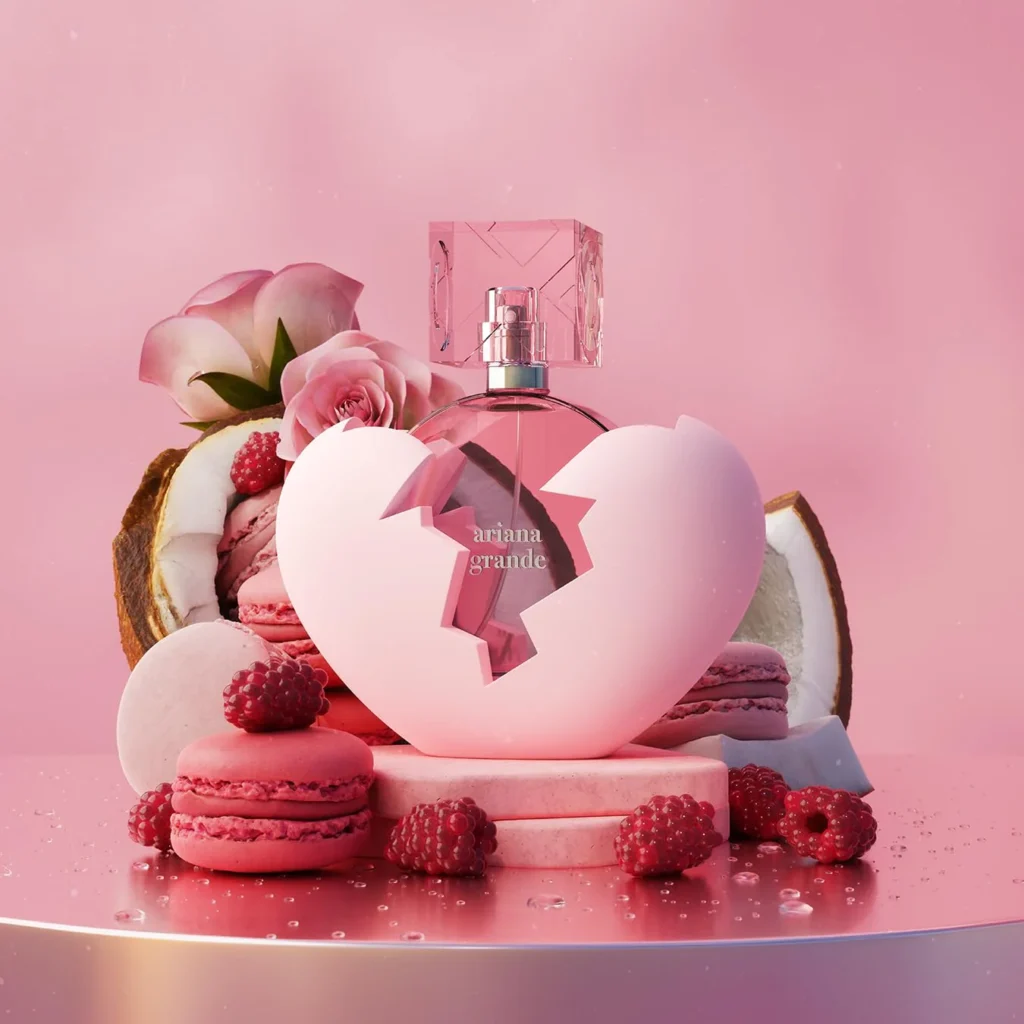 Ariana Grande perfume bottle from the Sweet Like Candy collection surrounded by pink macarons, roses, coconut, and raspberries.